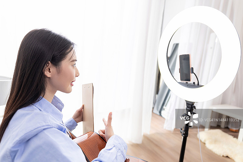 Vlog博主在家教弹吉他和唱歌，远程办公吉他老师图片素材