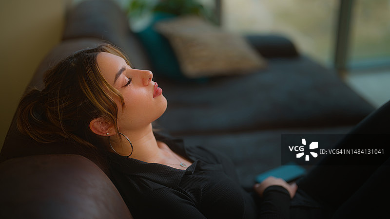 年轻女人在沙发上闭眼放松图片素材