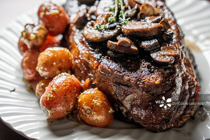白盘上的多汁肋眼牛排、炒蘑菇和小土豆图片素材