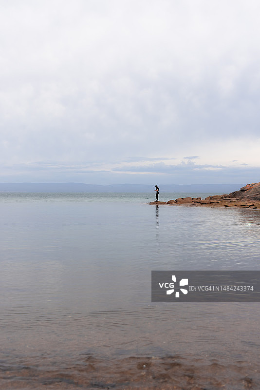 年轻女子在塔斯马尼亚蜜月湾的宁静海湾岩石上图片素材