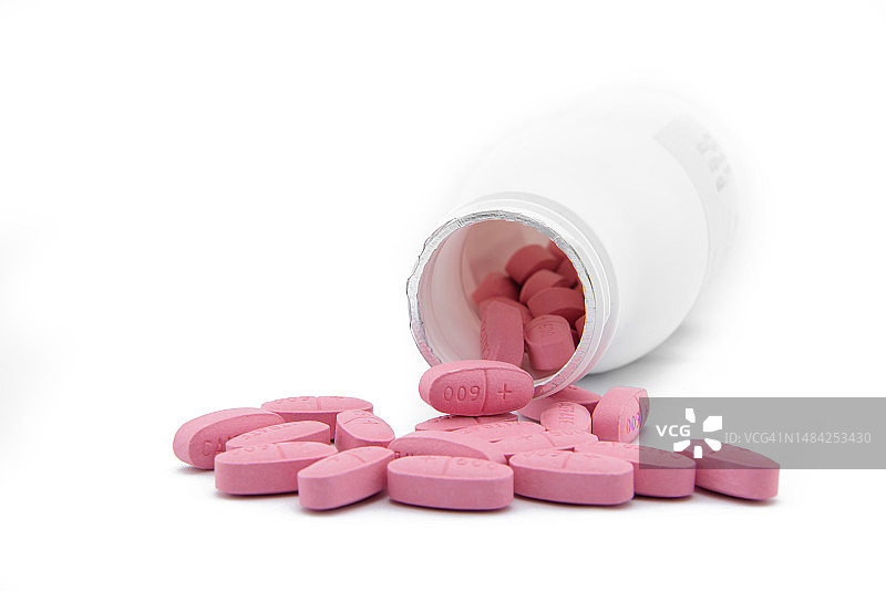 白色背景下药瓶倾倒的药丸特写图片素材