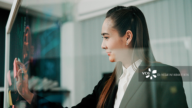 准备视觉辅助工具以帮助即将到来的商务会议的年轻亚裔女性图片素材