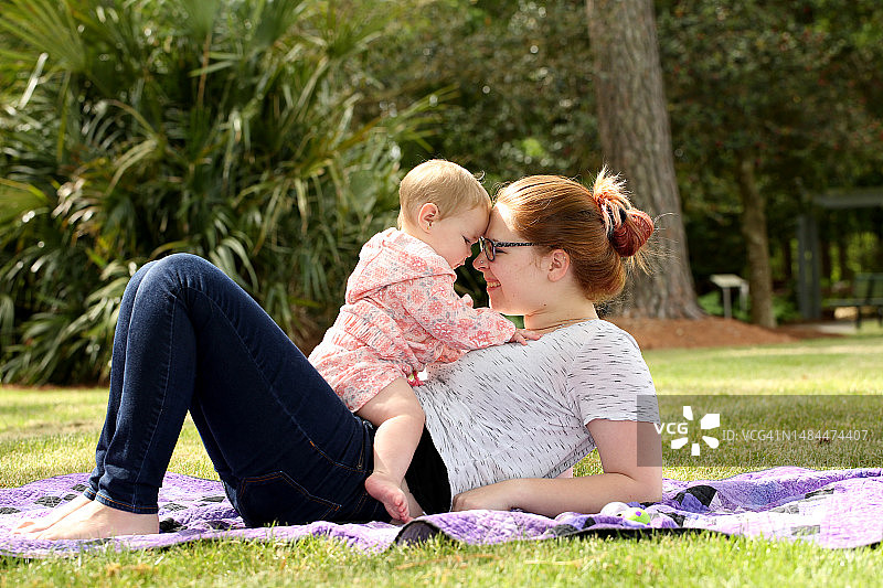 母亲在户外与新生女儿互动图片素材