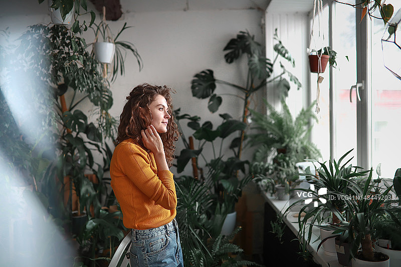 在家庭温室中拥有棕色长卷发的漂亮女人图片素材