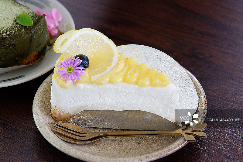 柠檬奶油芝士蛋糕，棕色盘子，木桌背景图片素材