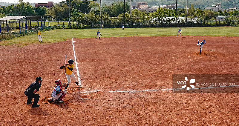 投手向击球手投球，击球手站在击球区准备击打比赛中地滚球的远景图片素材