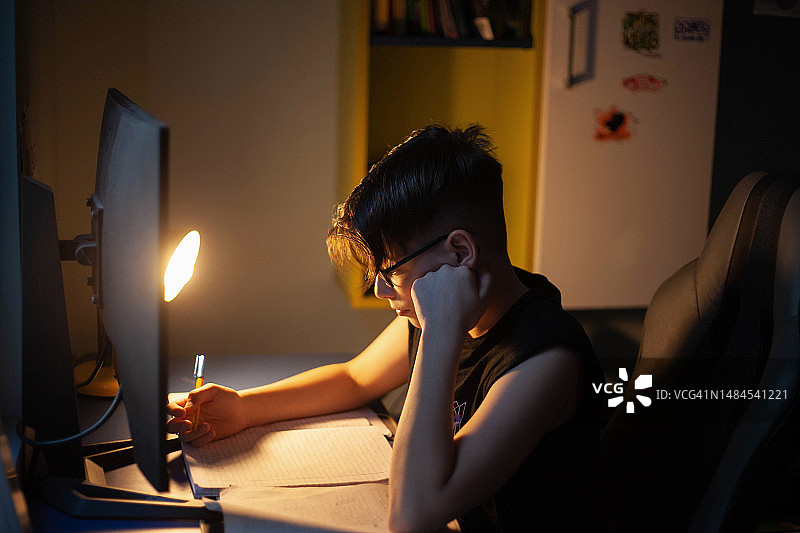 12-13岁的男孩在房间里做作业图片素材