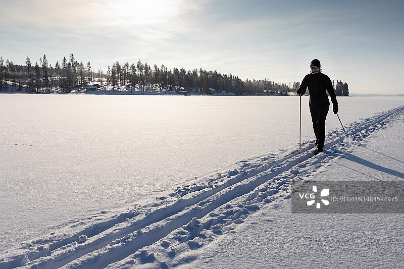在芬兰凯努区奥卢湖冰冻湖面上滑雪的女人图片素材