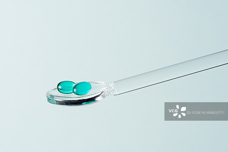 玻璃勺中的绿色软胶囊图片素材