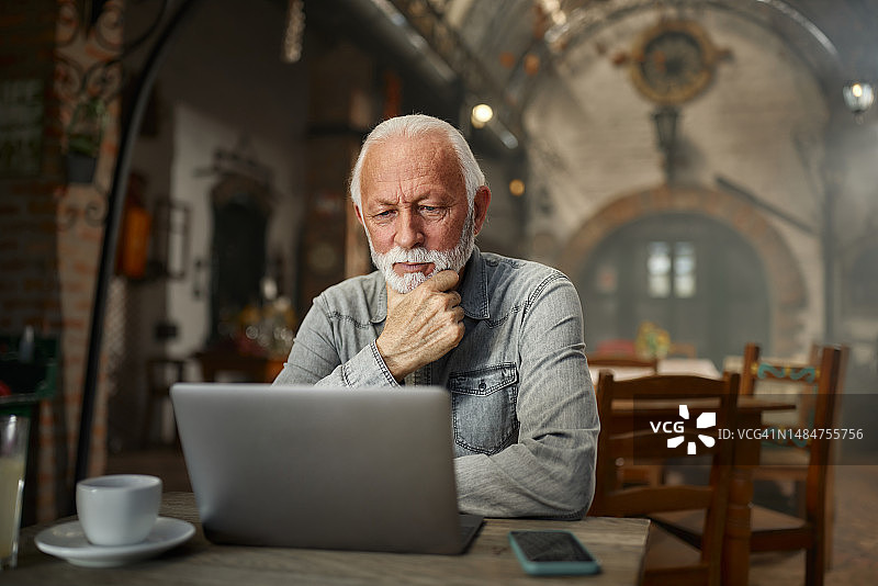 专注的中年男人在咖啡馆使用笔记本电脑图片素材
