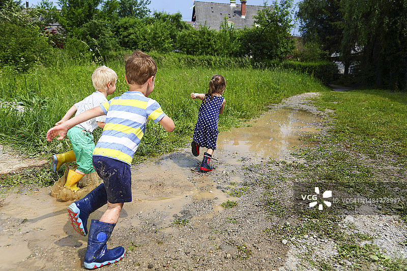 在泥泞的水坑里奔跑的儿童图片素材