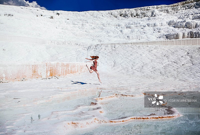 土耳其棉花堡白色石灰华梯田上赤脚奔跑的女人图片素材