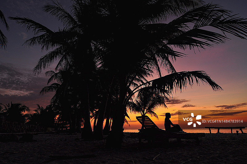 印尼罗特岛Nemberala海滩日落时坐在沙滩椅上的女子剪影图片素材