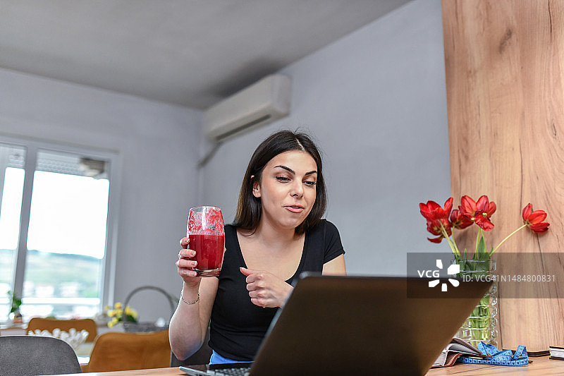 女人通过视频通话与营养师交流，饮用奶昔以减轻体重图片素材