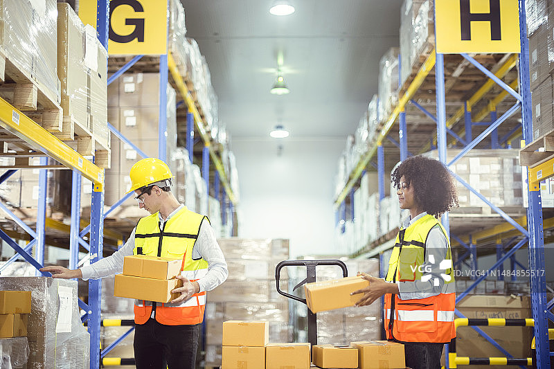 仓库内部，年轻非洲员工和英俊的年轻白人雇员一边计数，一边驾驶叉车，寻找货架，按产品类型准备发送给目的地的客户图片素材