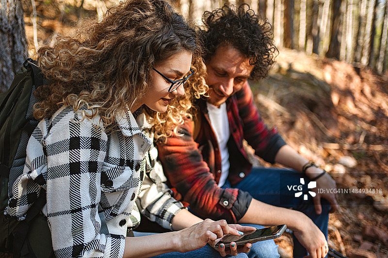 在森林里徒步旅行时查看在线地图的年轻情侣图片素材