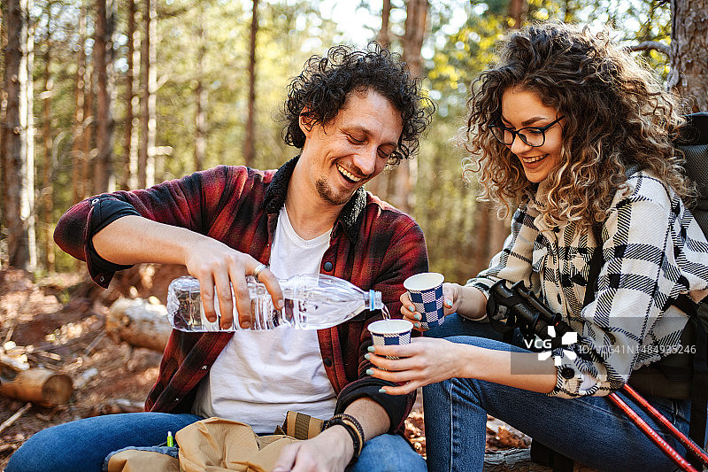 年轻情侣在森林徒步旅行后喝水放松图片素材