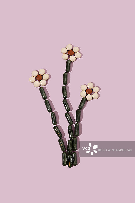 粉红色背景上的花朵形状的药丸图片素材