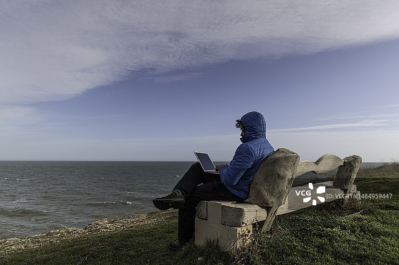 人物与自然：在海边使用笔记本电脑的男人图片素材