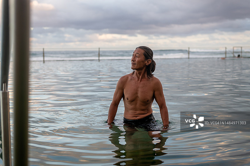 活跃的男子在岩石池中游泳图片素材