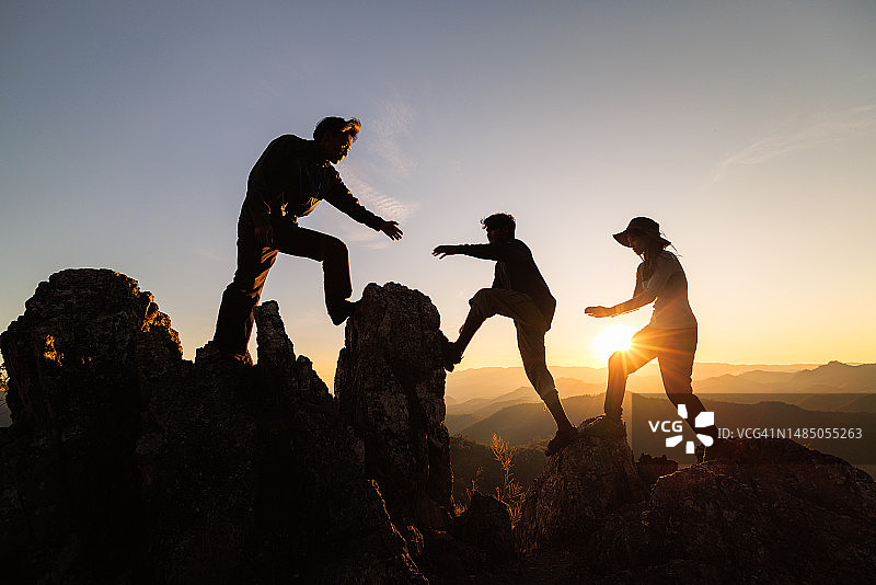登山者攀登悬崖的剪影：互助与团队合作图片素材