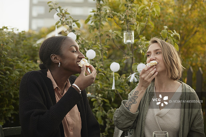 微笑的女人在花园里吃蛋糕图片素材
