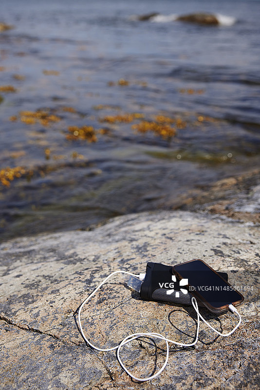 岩石海岸上的手机和充电宝图片素材