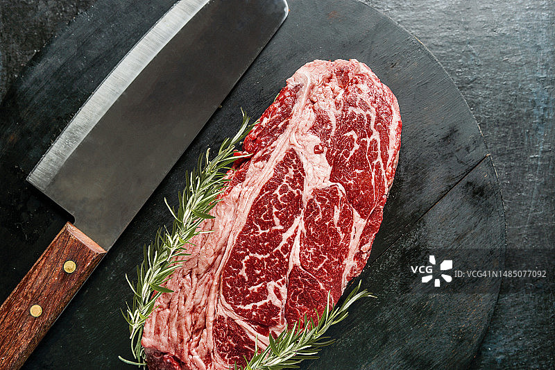 黑背景上的生牛排与刀和迷迭香图片素材