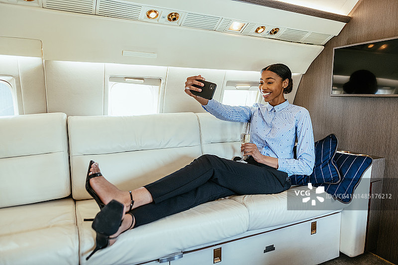 在私人飞机沙发上自拍的年轻非洲女商人图片素材