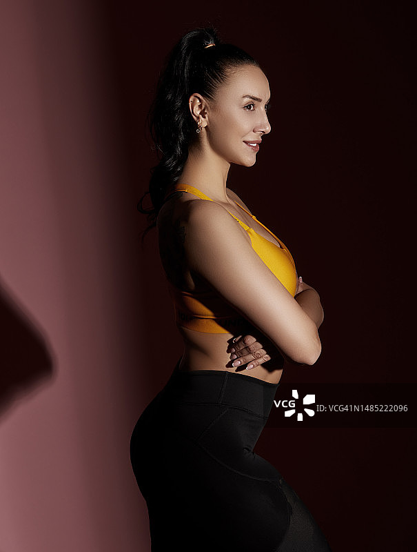 身穿运动服、手臂交叉、对着镜头微笑的年轻健康女性图片素材