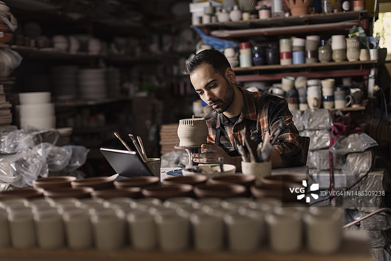 年轻陶艺家在工作室用工具制作泥杯图案图片素材