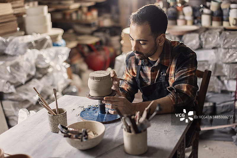 年轻陶艺家在工作室用工具制作泥杯图案图片素材