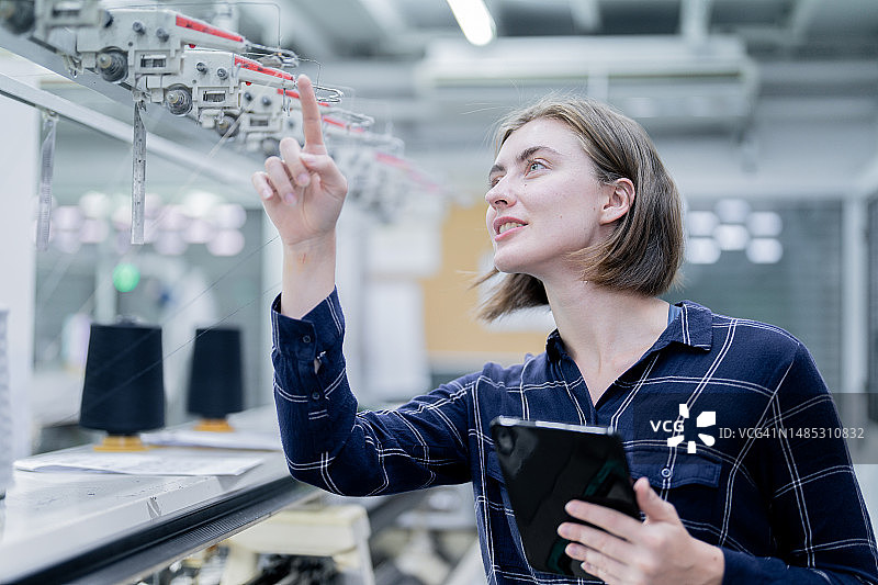 时装生产工人在织布机上进行质量把控图片素材