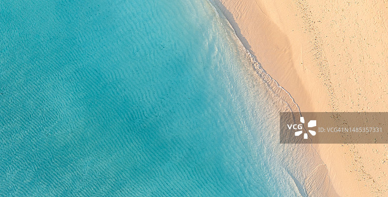 海滩海岸线鸟瞰图：热带岛屿海滩风光，绝佳的顶部景观，海浪拍打着沙滩，田园诗般的自然背景图片素材