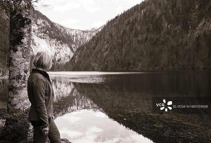 棕褐色调,站在奥地利施蒂利亚州萨尔茨卡默古特地区托普利茨湖岸边的女人图片素材