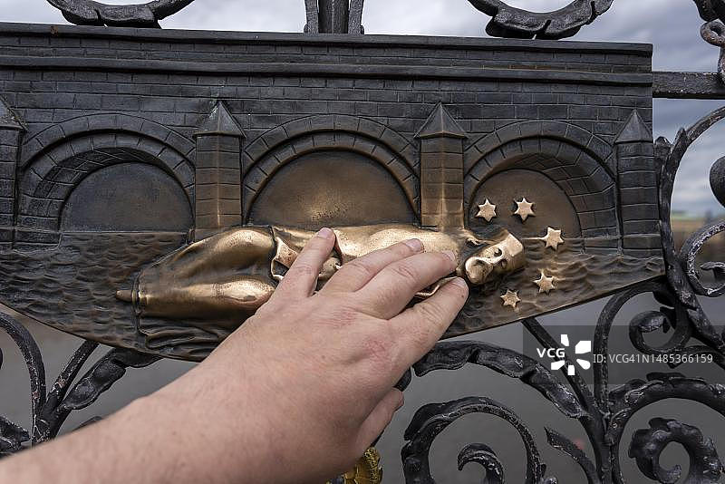手部触摸布拉格查理大桥上的内波穆克的圣约翰青铜浮雕，捷克共和国图片素材