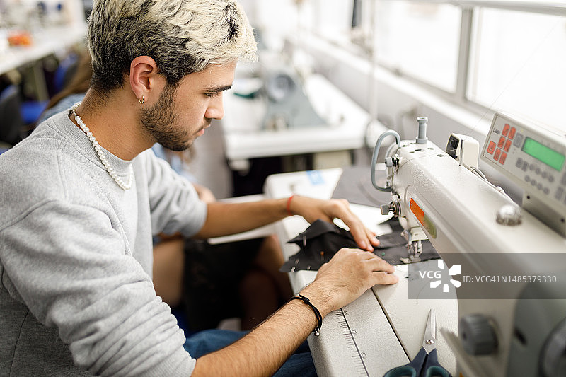 使用缝纫机的年轻男人图片素材