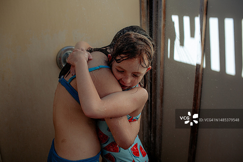 姐妹在户外淋浴时拥抱图片素材