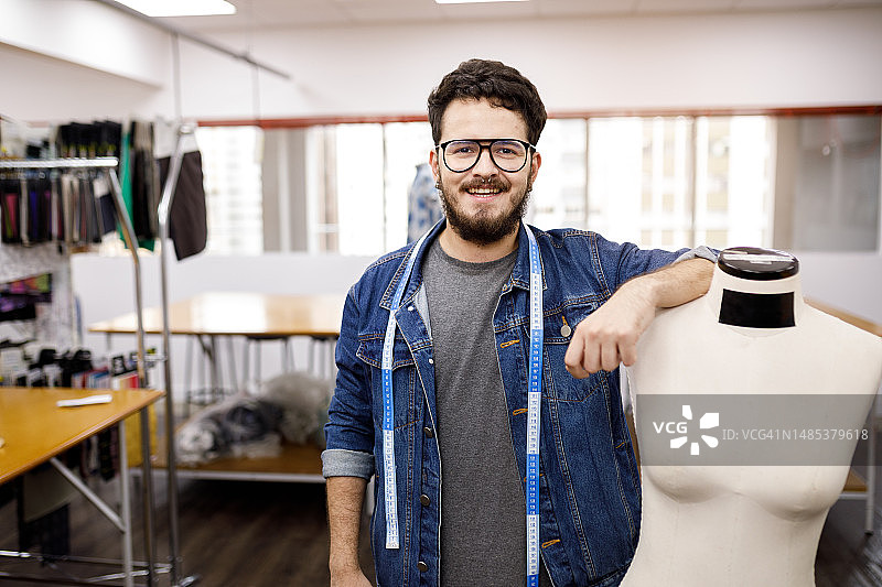 脖子上缠着卷尺，靠在人体模型上的男子图片素材