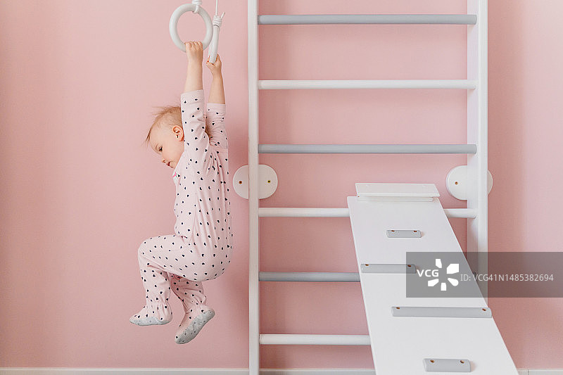 穿着粉色睡衣的白人女孩在吊环上做运动图片素材