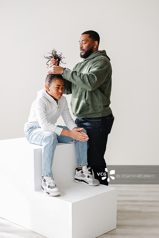 时尚的黑人爸爸为混血儿子理发图片素材