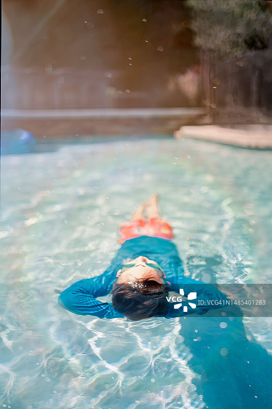 男孩仰卧在泳池中放松图片素材