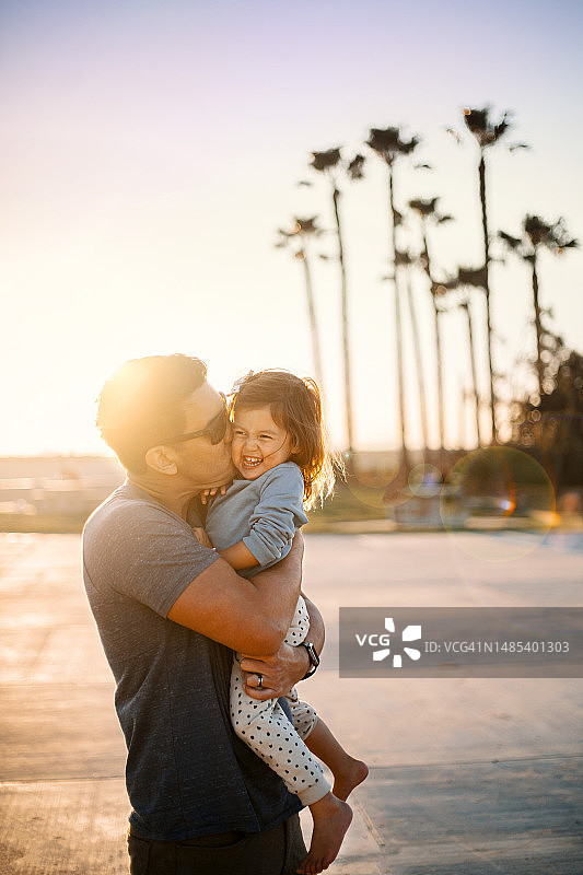 阳光下父亲亲吻女儿图片素材