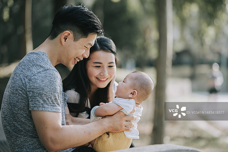 中国父母在周末早晨的公园里与男婴互动图片素材