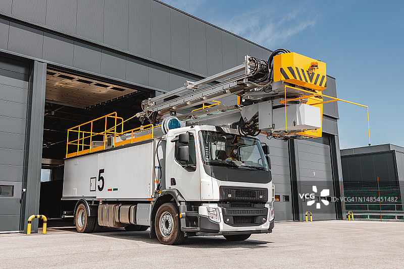 停在机场仓库外的带液压臂的除冰车图片素材