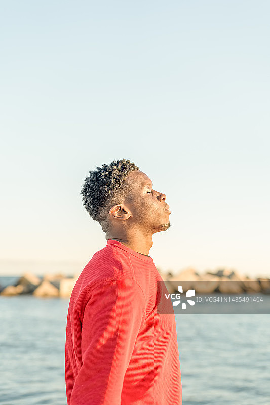 男人在户外大自然中闭着眼睛呼吸新鲜空气的肖像图片素材