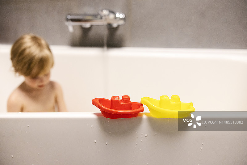 小男孩在浴缸里玩玩具船图片素材