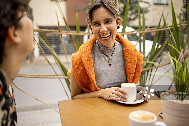 坐在当地咖啡馆里玩乐的两名年轻拉丁裔女子图片素材