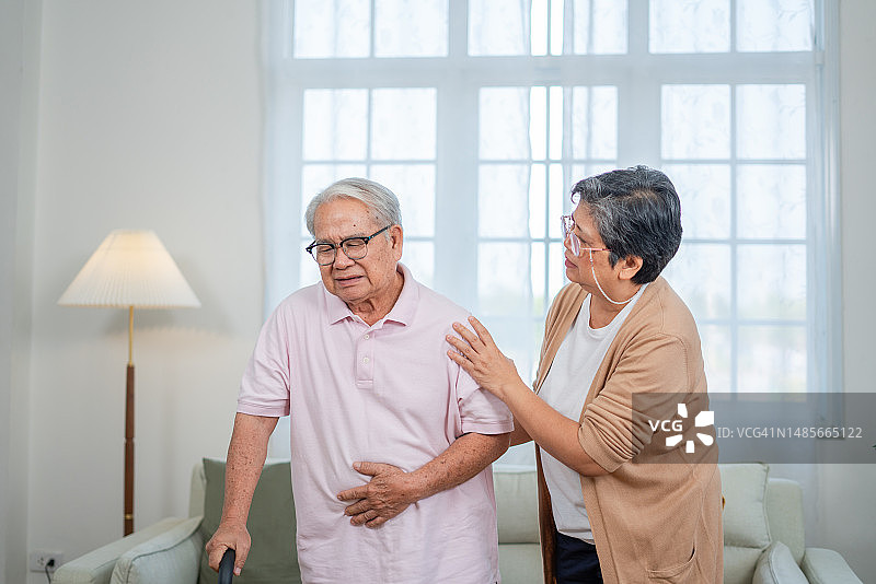 亚洲老年夫妇帮助丈夫从沙发上站起来缓解背痛图片素材
