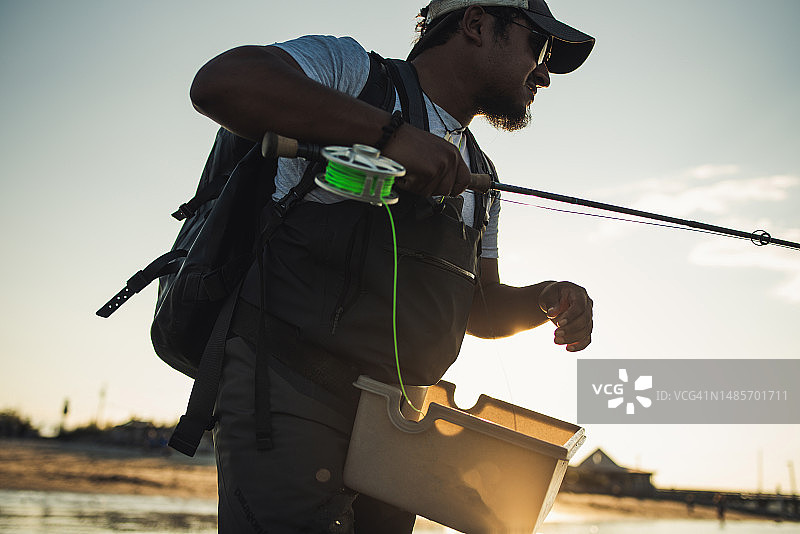 西班牙裔男人在海滩附近的海洋中飞蝇钓鱼图片素材